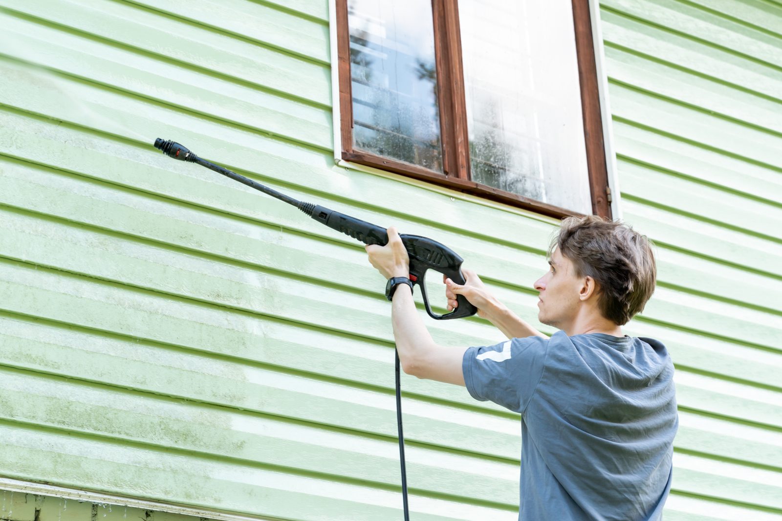 Technician soft washing siding on a Richmond house