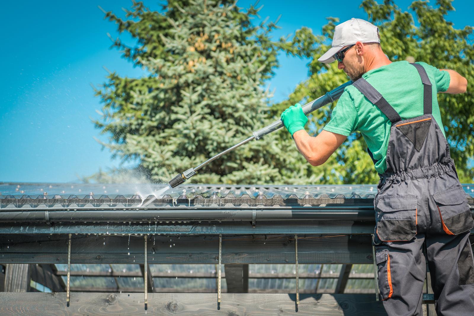 Roof being soft washed from a ladder